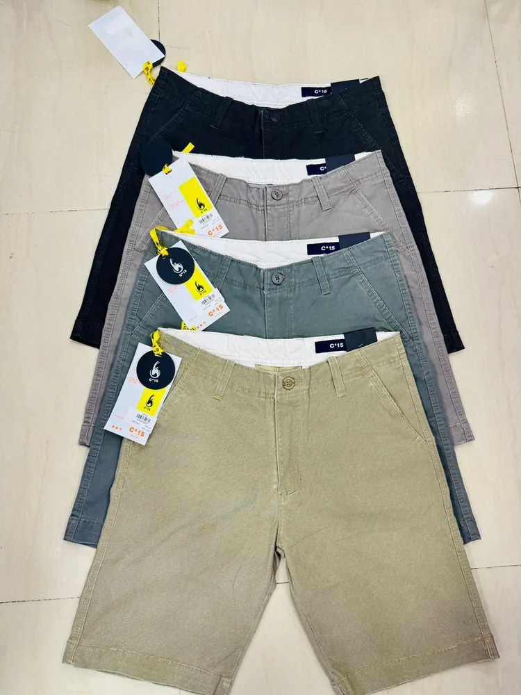 Stack of folded C-15 cotton half pants in navy, grey, green and khaki with swing tags