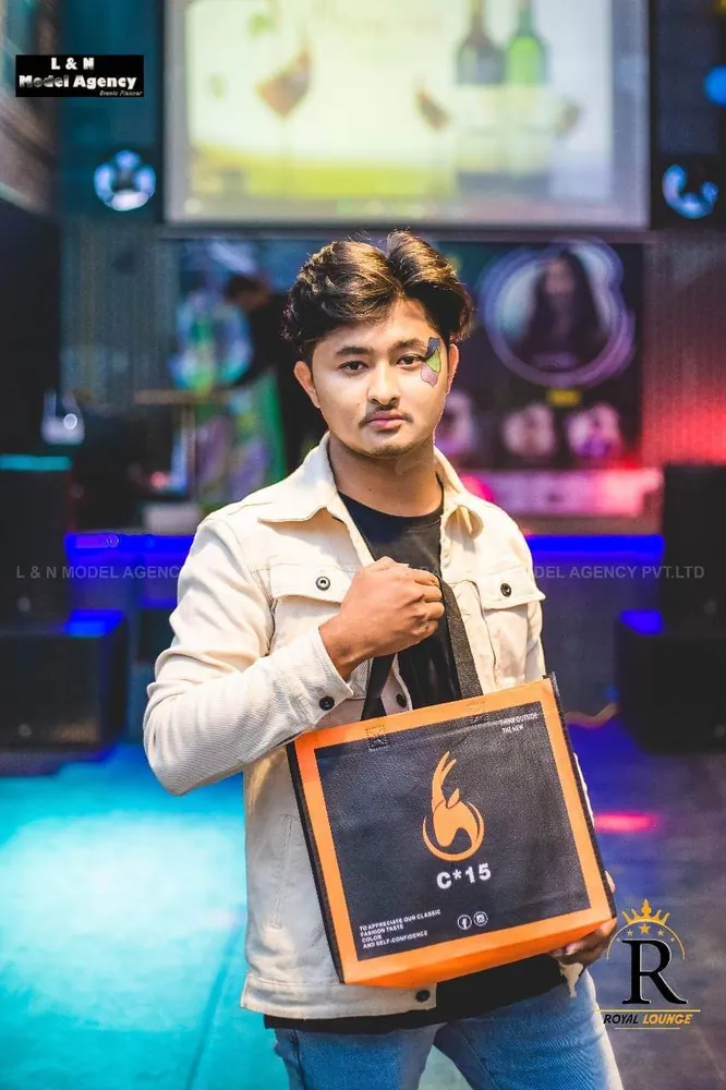 Man in a cream denim jacket holding the C-15 tote bag at an evening event