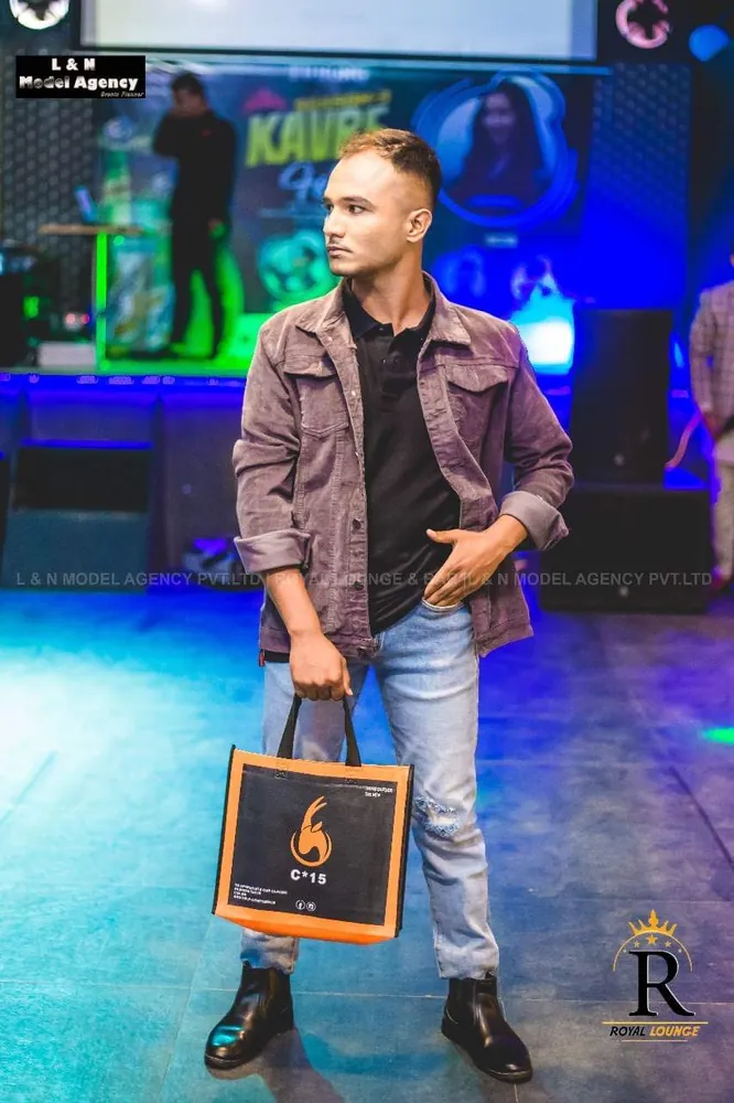 Man in a mauve jacket holding the C-15 tote bag under stage lights