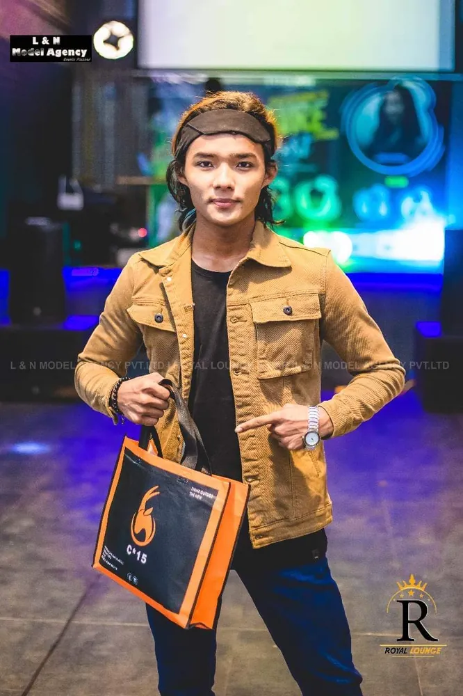 Man in a tan jacket and headband holding the C-15 tote bag at an event