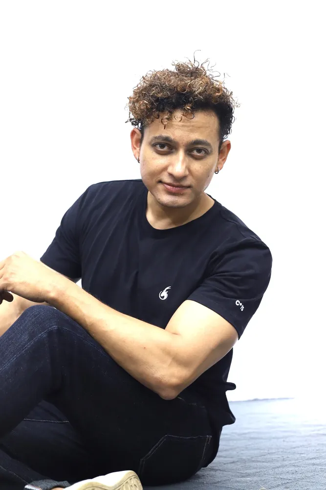 Model crouching in a black C-15 t-shirt and dark jeans against a white studio backdrop