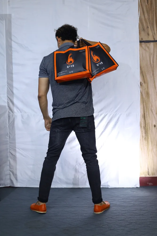 Model seen from behind carrying the orange C-15 tote bag over a grey t-shirt