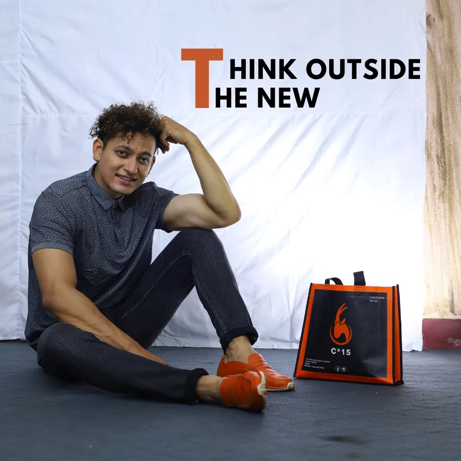 C-15 campaign poster of a model seated beside the orange C-15 tote bag with the words Think Outside The New